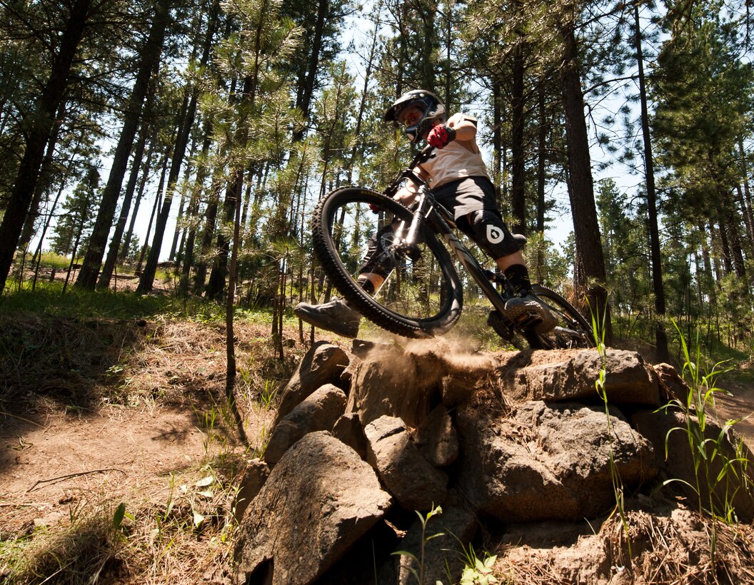 Senior Airman Justin Faircloth, 28th Operations Support Squadron air traffic control technician, flies off the side of a jump while mountain biking at Storm Mountain, S.D., June 24, 2012. Faircloth’s safety equipment, such as his helmet, gloves, and kneepads, would help protect him in the event of a crash. (U.S. Air Force photo by Airman 1st Class Alystria Maurer/Released)