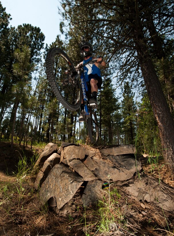 Airman 1st Class Brody Schneider, 28th Operations Support Squadron air traffic control technician, soars off a jump while mountain biking at Storm Mountain, S.D., June 24, 2012. Prior to every run, Schneider and his fellow cyclists scouted and planned out their path to ensure it was within their skill level. (U.S. Air Force photo by Airman 1st Class Alystria Maurer/Released)