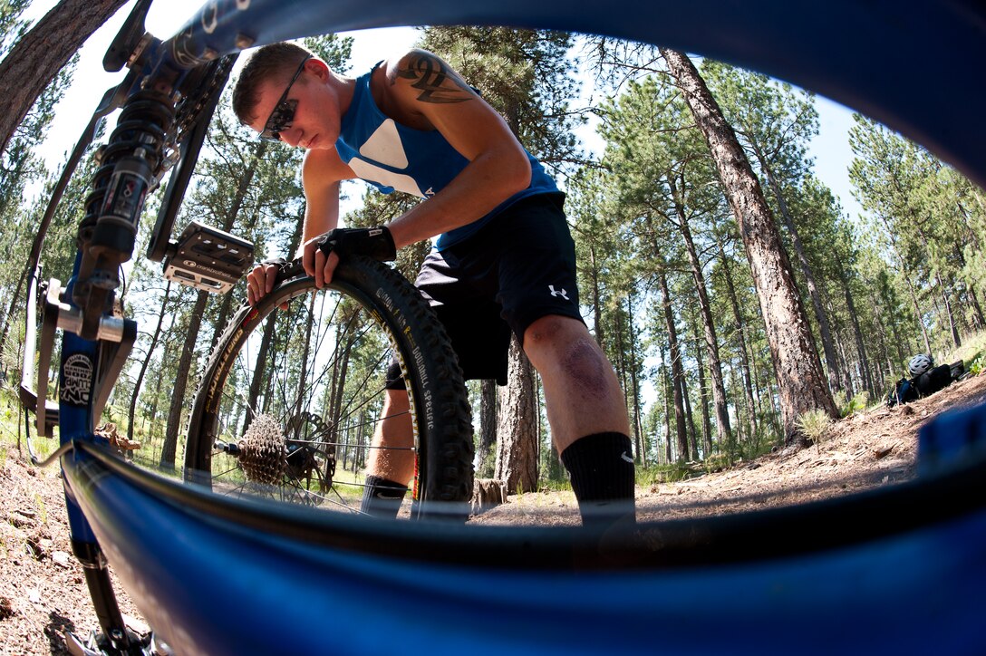 Airman 1st Class Brody Schneider, 28th Operations Support Squadron air traffic control technician, inserts a new inner tube into his bicycle tire after popping a tire while mountain biking at Storm Mountain, S.D., June 24, 2012. All Airmen are reminded to perform safety checks on all of their equipment prior to participating in outdoor activities. (U.S. Air Force photo by Airman 1st Class Alystria Maurer/Released)