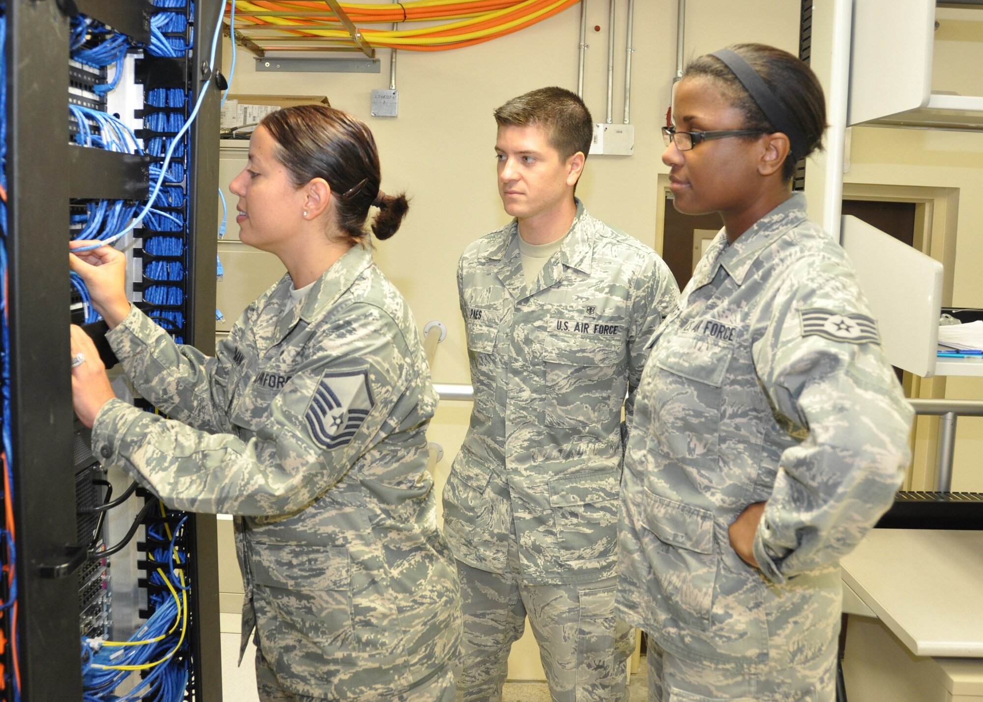 Master Sgt. Marisa Guzman, 81st Medical Support Squadron. left, trains Senior Airman Rodrigo Paes, center, and Staff Sgt. Alexis Ellsworth on server management in the 81st MDSS information systems server center June 19, 2012, at Keesler Air Force Base, Miss.  Guzman was selected into the nurse enlisted commissioning program June 13. (U.S. Air Force photo by Steve Pivnick)