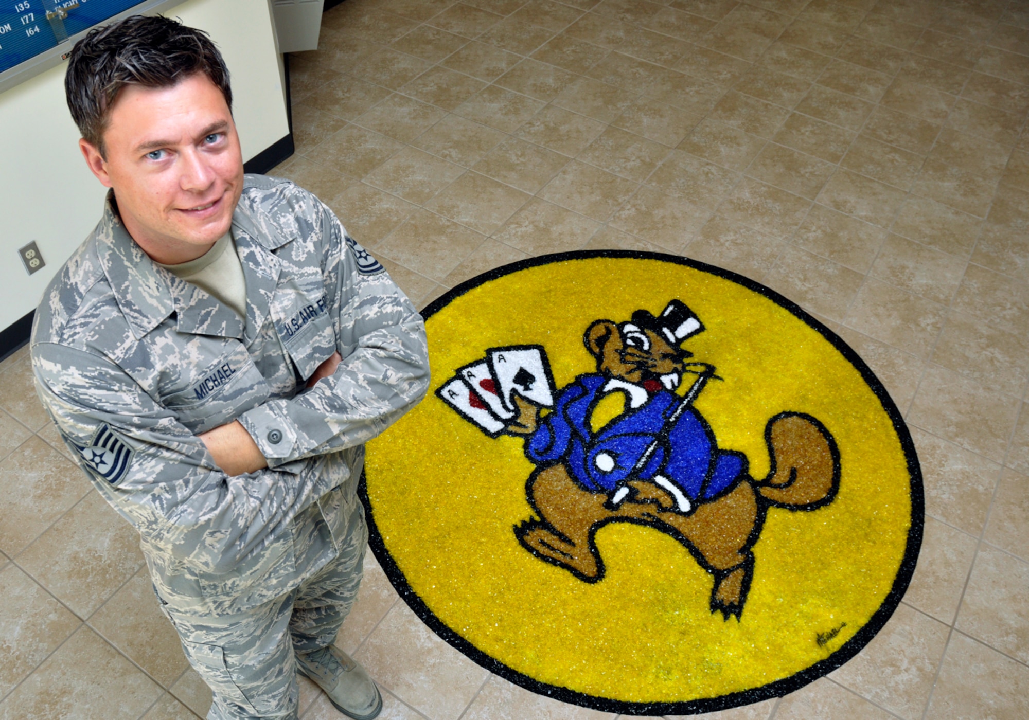 Technical Sergeant Michael T. Craig, 138th Fighter Wing Aircrew Flight Equipment Specialist, stands beside his latest artistic creation at the flight operations entrance at the 125th Fighter Squadron, Oklahoma Air National Guard, Tulsa, OK.  TSgt Craig has been adorning the facility with his work since he joined the unit in September 2008.