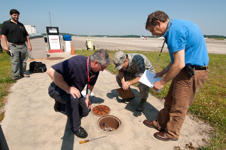 HANSCOM AIR FORCE BASE, Mass. – (left to right) Jim Maravelias, Civil Engineering; Steven Bates, Aero Club; Staff Sgt. Sean Carty, 66th Medical Squadron and team leader; and Robert Spelfogel, CE, look at the cover to an underground storage tank that stores aviation fuel during the Environmental Safety and Occupational Health Compliance Assessment Management Program inspection June 21. The review is used to determine Hanscom's compliance with environmental, safety and occupational health laws and regulations. (U.S. Air Force photo by Rick Berry)