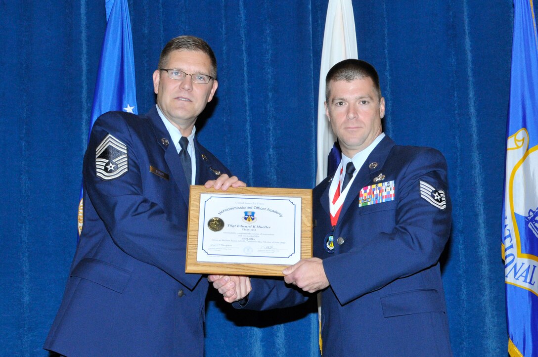 McGHEE TYSON AIR NATIONAL GUARD BASE, Tenn.- Tech. Sgt. Edward Mueller, right, receives the distinguished graduate award for NCO Academy Class 12-5 at the I.G. Brown Training and Education Center here from Chief Master Sgt. Thomas K. Stoudt, June 7, 2012.  The distinguished graduate award is presented to students in the top ten percent of the class.  It is based on objective and performance evaluations, demonstrated leadership, and performance as a team player. (Air National Guard photo by Master Sgt. Kurt Skoglund/Released)