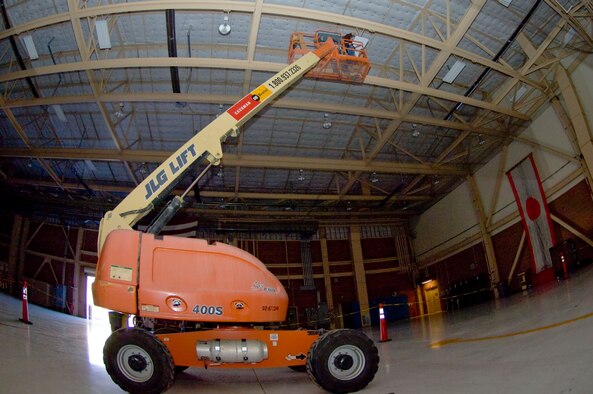 Electricians atop a lift install new lighting fixtures into a hangar at Nellis Air Force Base, Nev., June 20, 2012. The hangar lighting is being replaced with more energy efficient lighting in an effort to reduce Nellis energy use by 30 percent as of fiscal year 2015. (U.S. Air Force photo by Senior Airman Jack Sanders/Released) 

