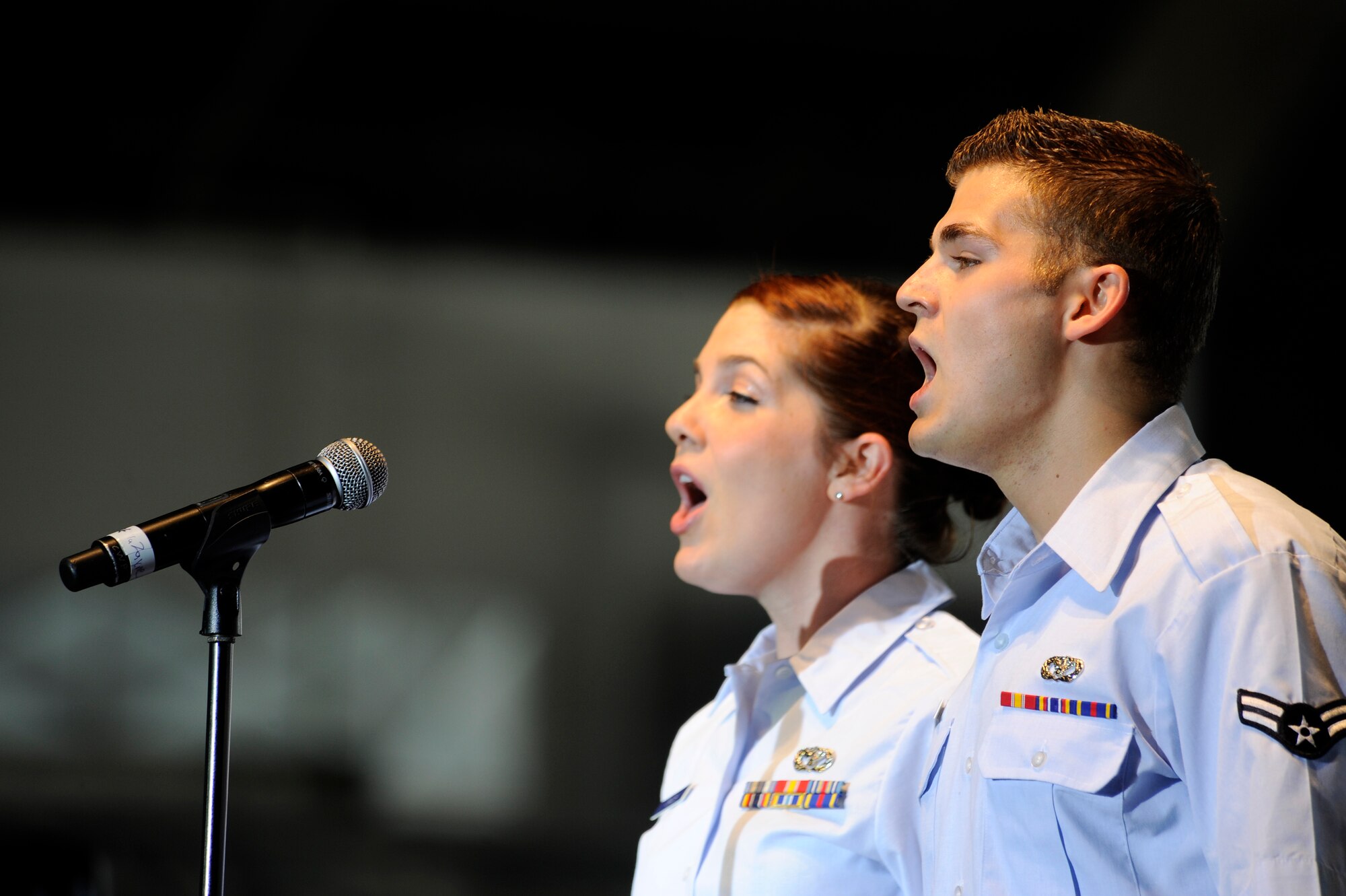 U.S. Air Force Senior Airman Aimee Grills and Airman 1st Class Daniel Sokolowski, 354th Civil Engineer Squadron geobase technicians, sing the national anthem during the Gary Sinise and Lt. Dan Band concert June 23, 2012, Eielson Air Force Base, Alaska. (U.S. Air Force photo/ Staff Sgt. Jim Araos)