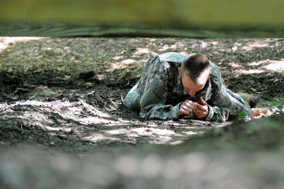 U.S. Army Sgt. 1st Class Adam McQuiston, Fort Leonard Wood, Mo., drill instructor, low crawls under an obstacle on the confidence course located at Fort Eustis, Va., June 27, 2012, as part of the annual Drill Sergeant of the Year competition, hosted by Initial Military Training, U.S. Army Training and Doctrine Command. During the course competitors had to do things like; low crawl, cross monkey bars, climb walls and jump ditches.(U.S. Air Force photo by Senior Airman Wesley Farnsworth/Released)