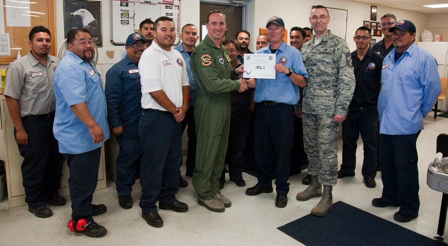 Darin Casillas, 47th Maintenance Directorate aircraft attendant, poses with Col. Tom Murphy, 47th Flying Training Wing commander, and Chief Master Sgt. Garry Berry, 47th FTW command chief, after being presented the XLer of the week award at Laughlin Air Force Base, Texas, June 20, 2012. The XLer is a weekly award chosen by wing leadership and given to those who consistently make outstanding contributions to Laughlin and their unit. (U.S. Air Force photo/Airman 1st Class Nathan Maysonet)