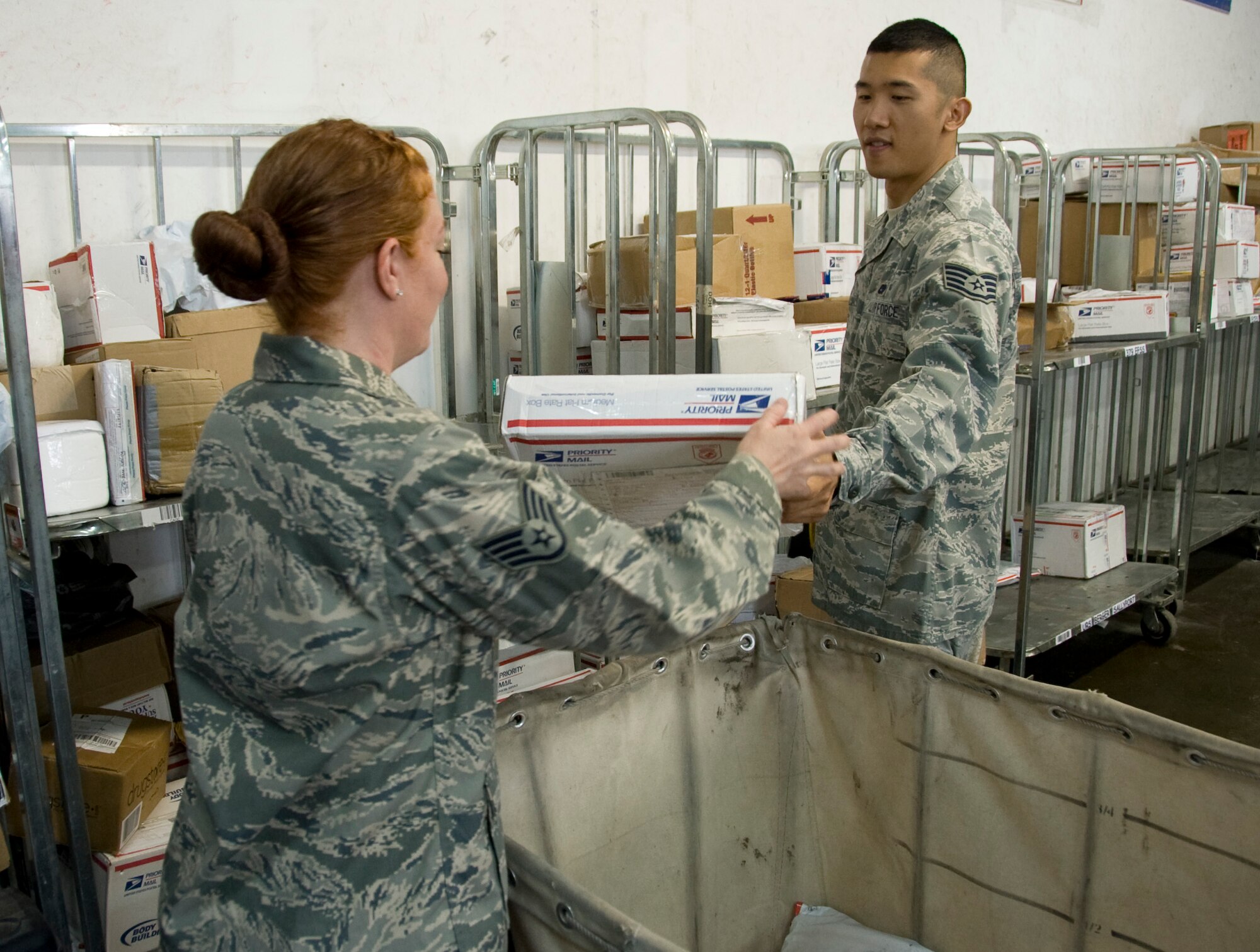 Staff Sgt. Melissa Spell (left) and Staff Sgt. Chang Kim, 379th ECS postal clerks, sort through delivered parcels to get them ready for pickup by the units here. The post office here provides postal service for 60 units and all branches of military. (U.S. Air Force photo/Senior Airman Bryan Swink) 