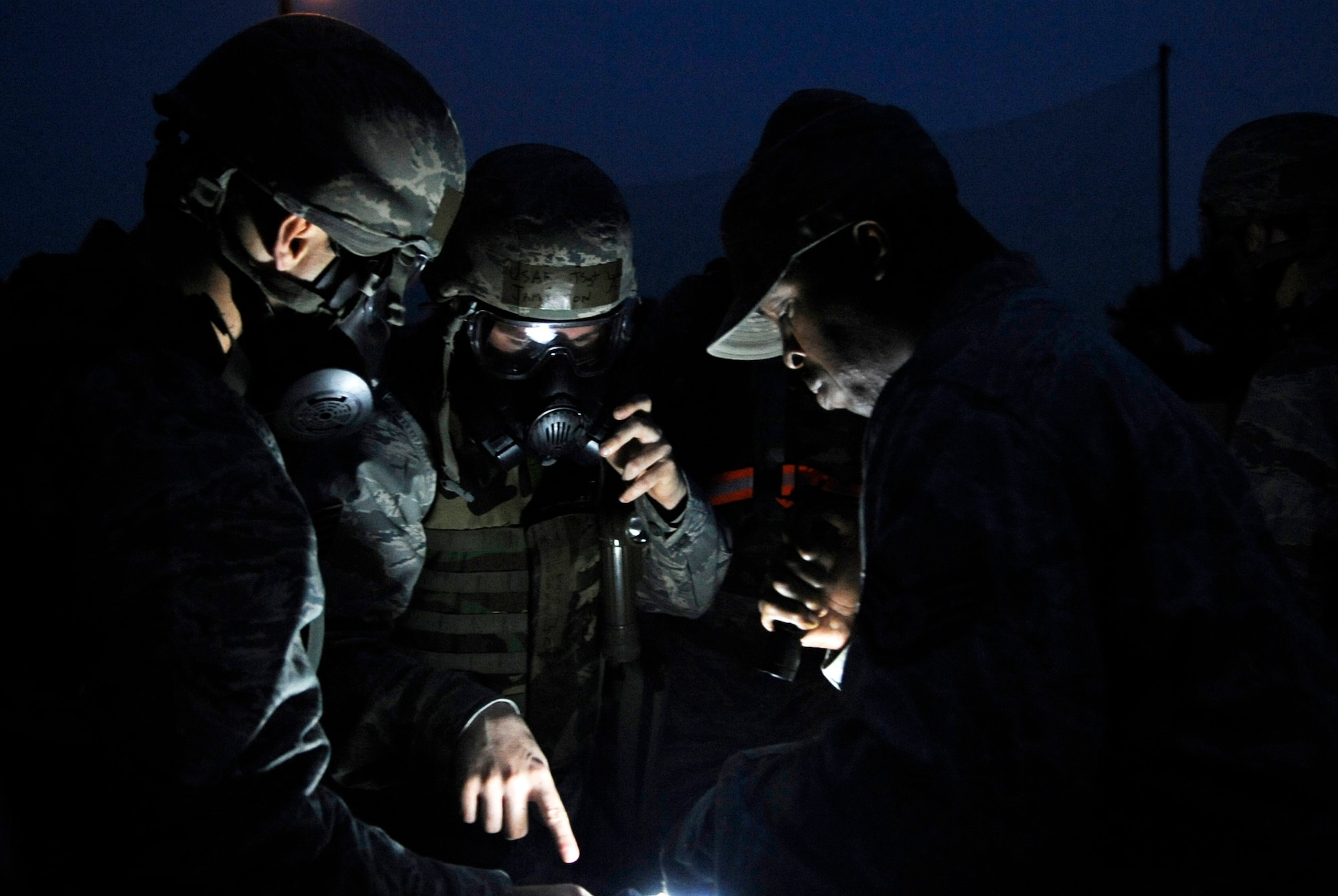 Airmen from the 8th Civil Engineer Squadron read M-8 chemical detection paper during nighttime contingency operations training June 21, 2012, at Kunsan Air Base, Republic of Korea. Being able to operate at night in mission-oriented protective posture is an important skill. (U.S. Air Force photo/Senior Airman Brigitte N. Brantley)