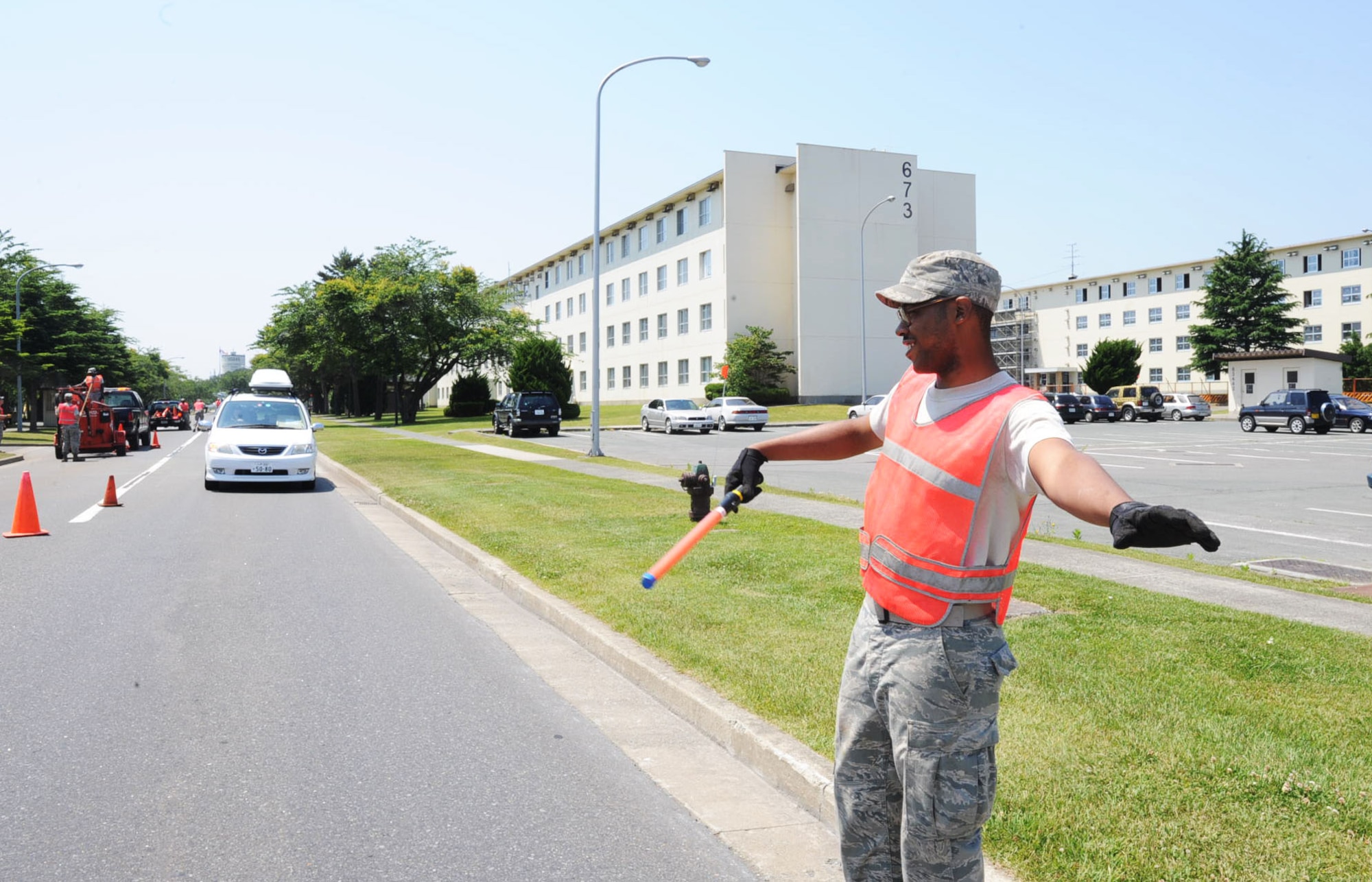 U.S. Air Force Airman 1st Class Edward Bistow, 35th Civil Engineer Squadron pavement and construction shop member, directs traffic on Freedom Drive while his team works on repairing the cracks at Misawa Air Base, Japan, June 27, 2012. The road repair of Freedom Drive is scheduled to be completed sometime in the next few days. (U.S. Air Force photo by Airman 1st Class Kenna Jackson/Released)