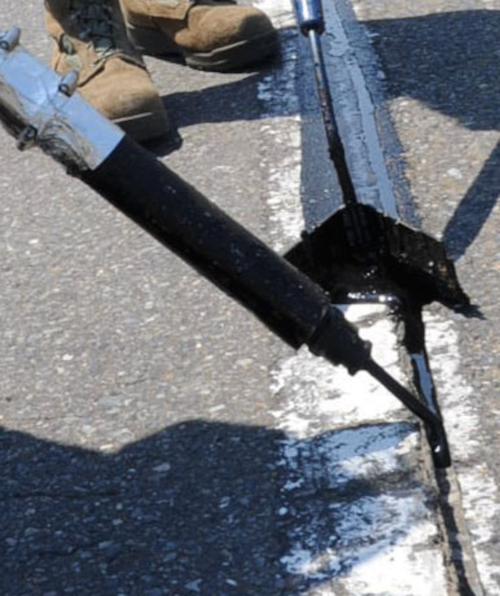 Members of the 35th Civil Engineer Squadron pavement and construction shop fill cracks in the road on Freedom Drive with hot asphalt at Misawa Air Base, Japan, June 27, 2012. This project is done every summer throughout the base to expand the life cycle of the roads. The hot asphalt sealant can only be applied to roads when the outside temperature is 65 degrees Fahrenheit or higher. (U.S. Air Force photo by Airman 1st Class Kenna Jackson/Released)