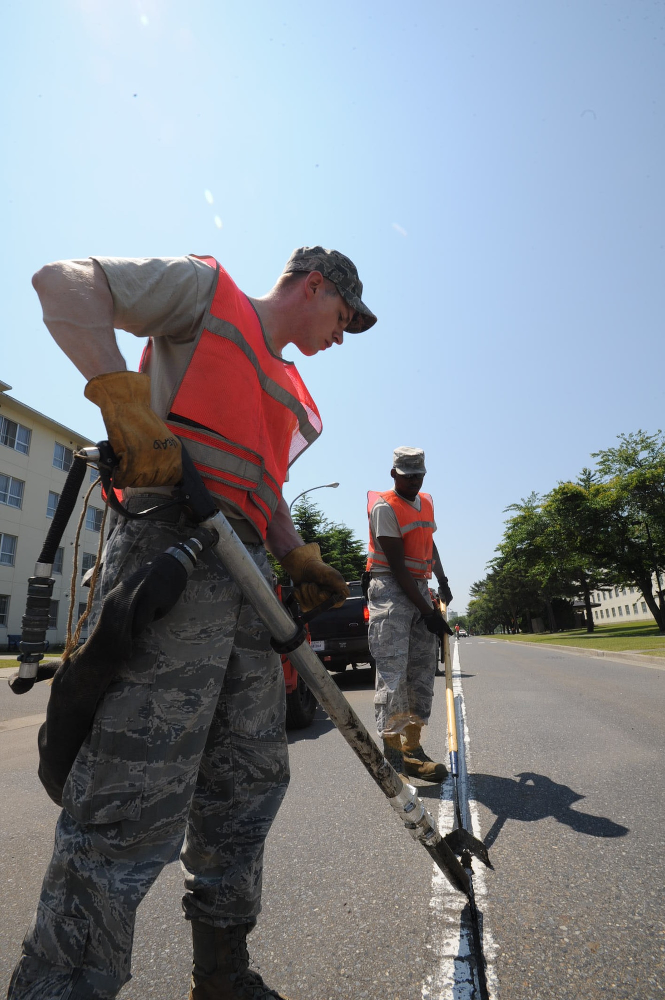 U.S. Air Force Staff Sgt. Paul Head, front, and Senior Airman Clifford Weston, 35th Civil Engineer Squadron pavement and construction shop members, apply hot asphalt sealant in cracks on Freedom Drive at Misawa Air Base, Japan, June 27, 2012. The hot asphalt sealant is heated up to 300 degrees Fahrenheit prior to application to roads. The sealant may take up to four hours to cool. (U.S. Air Force photo by Airman 1st Class Kenna Jackson/Released)