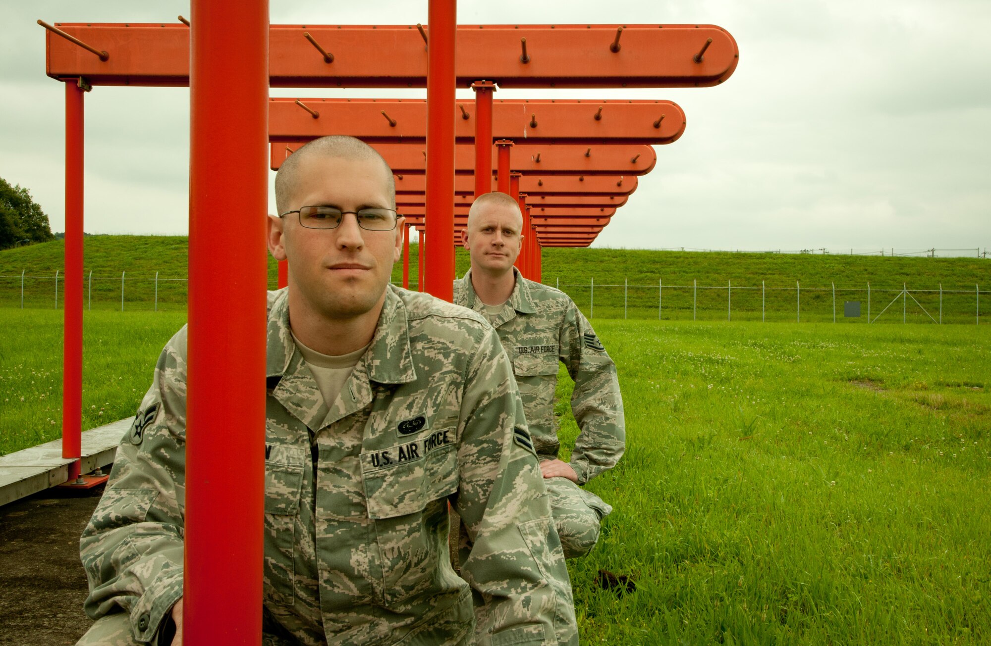 YOKOTA AIR BASE, Japan -- Airman 1st Class Lucas Dugan, left, 374th Communications Squadron airfield systems technician, and Staff Sgt. Robert Miller, right, 374th CS airfield systems supervisor, sit on the instrument landing system localizer at Yokota Air Base, Japan, June 25, 2012.  When a pilot can't see the runway at night or in bad weather conditions, they rely on the localizer; a system that sends out a signal for five nautical miles helping pilots find their way to Yokota. Miller and Dugan are responsible for maintaining this important piece of equipment. If it malfunctions at the wrong moment, people's lives could be at stake.  (U.S. Air Force photo by Staff Sgt. Shawn Rhodes)