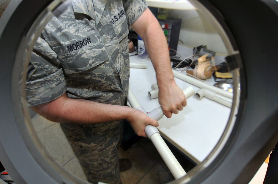 Staff Sgt. Lucas Morrow, American Forces Network broadcaster, fits pieces of PVC pipe together to create a custom camera stabilizing system at Osan Air Base, Republic of Korea, June 27, 2012. The innovator crafted the custom device in the AFN workshop for $4 dollars with PVC pipe and recycled materials. A professional-grade camera stabilizing system costs approximately $2,500 dollars. (U.S. Air Force photo/Staff Sgt. Craig Cisek)