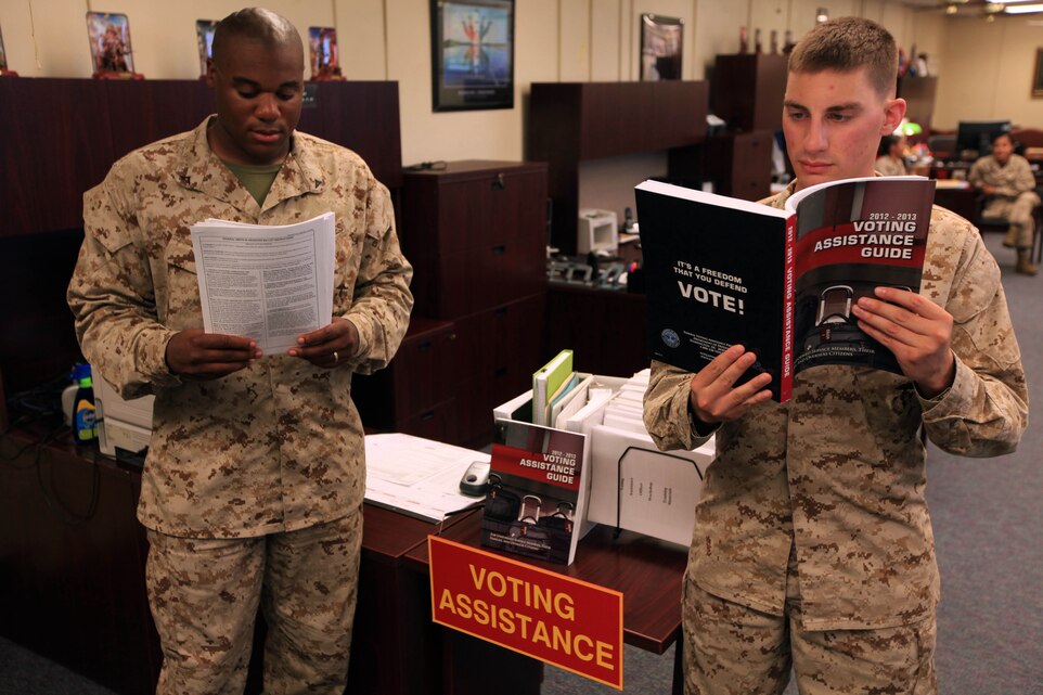 David Bierwirth and Patrick Seay, administrative specialists with Headquarters and Support Battalion, Marine Corps Installations - West, Marine Corps Base Camp Pendleton, gather information from the Installation Voter Assistance Office during Armed Forces and Overseas Civilian Voters Week, June 28 through July 7. This week focuses on increasing voter awareness throughout military installations and providing federal post card application assistance to eligible voters.
