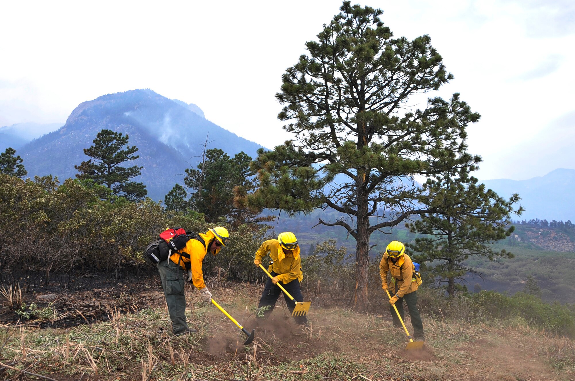 Tech. Sgt. Jason Linta, Bobby Garza, and Dean Prestia cut lines to create a firebreak to prevent fires from jumping at the U.S. Air Force Academy, Colo., June 28. Sergeant Linta is a firefighter assigned to the Air Force Academy and Garza and Prestia are firefighters assigned to Buckley Air Force Base, Colo. The Waldo Canyon fire has destroyed more than 18,000 acres in the Colorado Springs area. (U.S. Air Force photo by Staff Sgt. Christopher Boitz)
