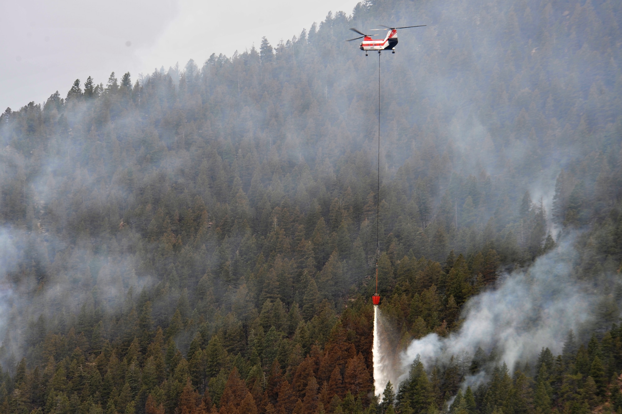 A helicopter dumps water on the Waldo Canyon Fire that has spread to the outskirts of the Air Force Academy, Colo., June 28. The Waldo Canyon fire has destroyed more than 18,000 acres in the Colorado Springs area. (U.S. Air Force photo by Staff Sgt. Christopher Boitz)