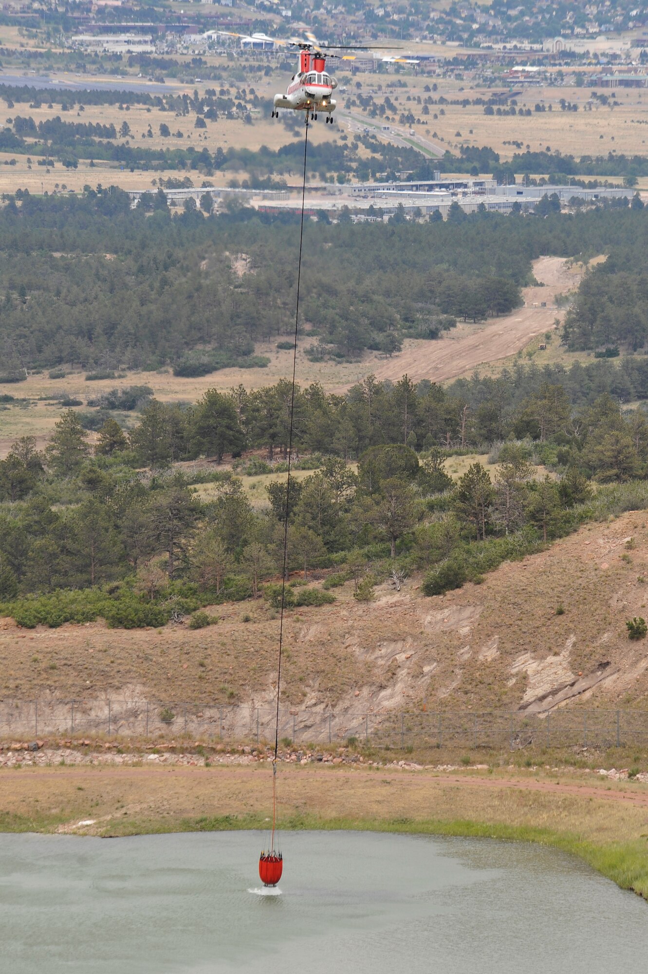 A helicopter hoists water from the Air Force Academy water treatment plant to dump on the Waldo Canyon Fire June 28. The Waldo Canyon fire has destroyed over 18,000 acres in the Colorado Springs area. (U.S. Air Force photo by Staff Sgt. Christopher Boitz)