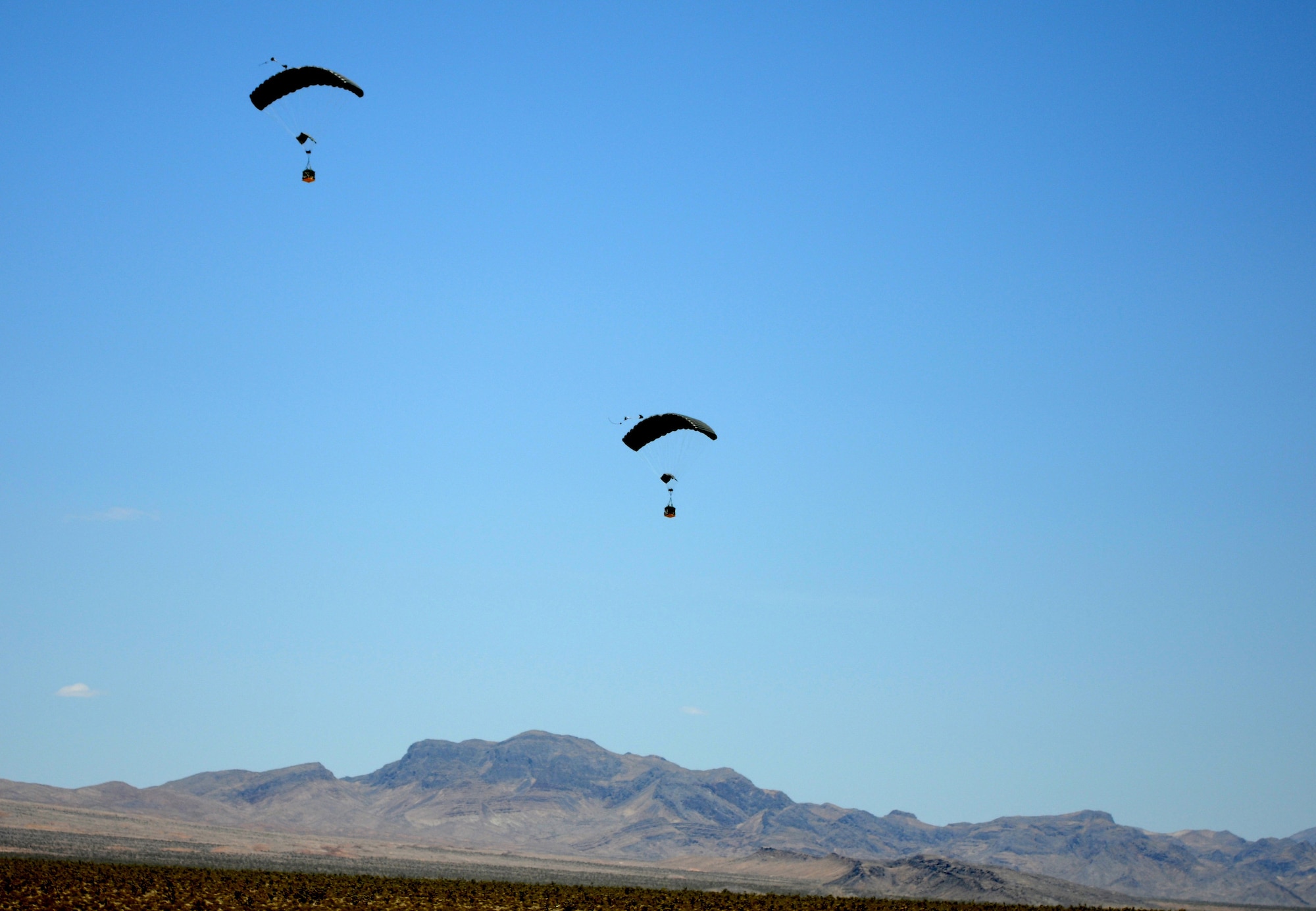 Two JPADS slowly guide themselves to the ground following their drop from a C-130J aircraft June 16, 2012, in Las Vegas, Nev. The JPADS are unique in that they are equipped with GPS units allowing them to drift to a specific point set by the user. (U.S. Army photo/Spc. David McCarthy)


