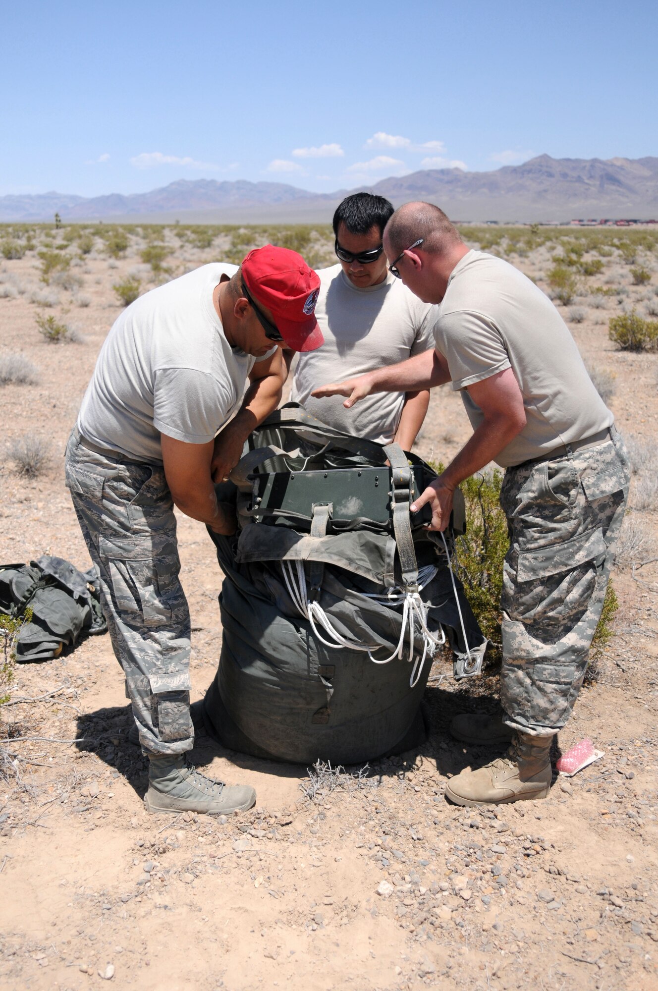 Soldiers and Airmen work together to pack up the parachutes used in the JPADS shortly after it landed on the drop zone June 16, 2012, in Las Vegas, Nev. The two services worked together to enhance their interoperability. (U.S. Army photo/Spc. David McCarthy)


