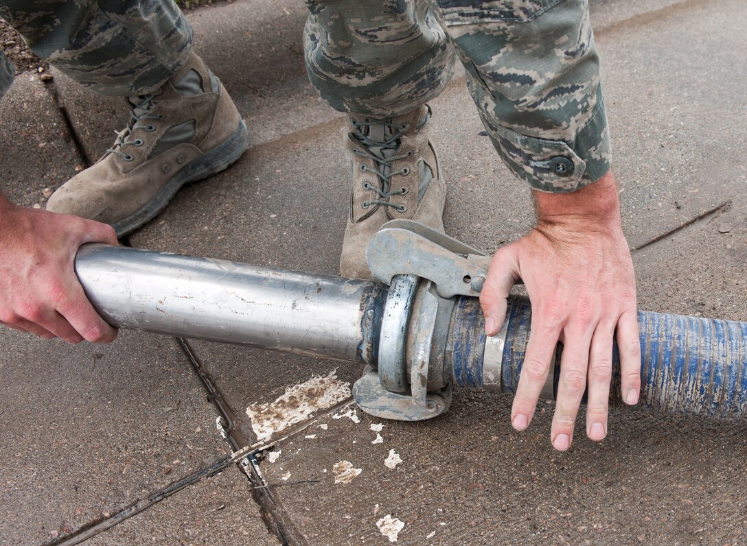 Senior Airman Joshua Peterson, 28th Civil Engineer Squadron water and fuels systems technician, attaches a nozzle to a hard wall hose during maintenance at Ellsworth Air Force Base, S.D., June 27, 2012. The hose is used to vacuum out debris such as leaves and garbage to prevent the sewer system from being clogged. (U.S. Air Force photo by Airman 1st Class Alystria Maurer/Released)
