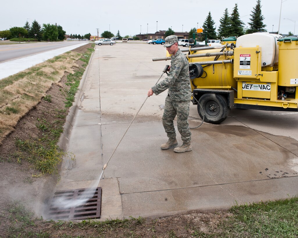 Senior Airman Joshua Peterson, 28th Civil Engineer Squadron water and fuels systems technician, pressure washes a storm drain during routine maintenance at Ellsworth Air Force Base, S.D., June 27, 2012. This drain was overflowing with water from recent heavy storms, and needed to be cleaned out to ensure it met environmental compliance standards. (U.S. Air Force photo by Airman 1st Class Alystria Maurer/Released)