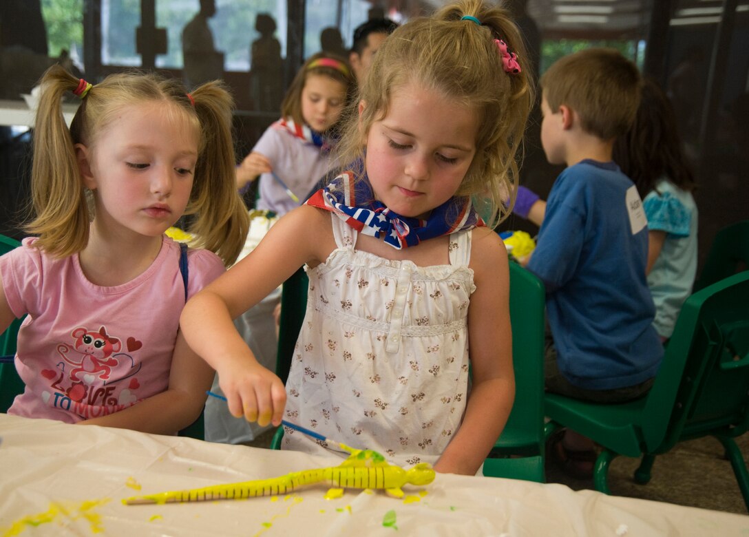 Lily Dilday, 5, observes as Callie Sollberge, 4, paints a toy dinosaur during arts-and-crafts time during a Summer Camp Experience event held at the Community Activity Center here, June 21. The camp, sponsored by the Andrews Exceptional Family Member Program, is held to promote fun and encourage childhood interaction. Lily is the daughter of Navy Cryptologic Technician Maintenance 1st Class Randal Dilday, Office of Naval Intelligence, Washington, D.C.  Callie is the daughter of Army Sgt. Brad Sollberger, mental health specialist, Fort George G. Meade Kimbrough Ambulatory Care Center. (Photo/Bobby Jones)
