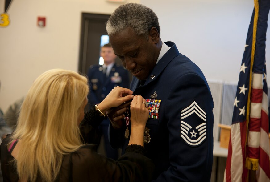 Retired U.S. Air Force Chief Master Sgt. John Hampton, Air Combat Command security forces manager, receives his retirement pin from his wife Christina at Moody Air Force Base, Ga., June 27, 2012. Hampton served 29 years on active duty and has been stationed at 15 bases. (U.S. Air Force photo by Airman 1st Class Paul Francis/Released)
