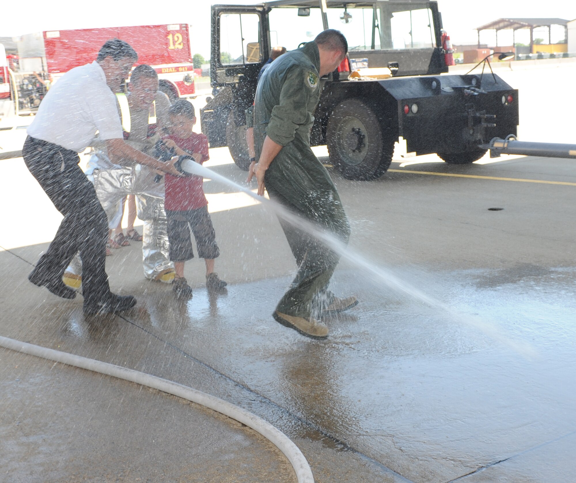 Rick Pettyjohn, 633rd Civil Engineer Squadron assistant chief of fire prevention, and Airman 1st Class Joshua Shelton, 633rd CES firefighter, help Wyatt, 8, soak his father, Lt. Col. Peter Fesler, 1st Operations Group deputy commander, with water after his final flight at Langley Air Force Base, Va., June 27, 2012. Fesler will relocate to his next assignment at the National War College, Washington, D.C. (U.S. Air Force photo by Airman 1st Class Teresa Cleveland/Released)