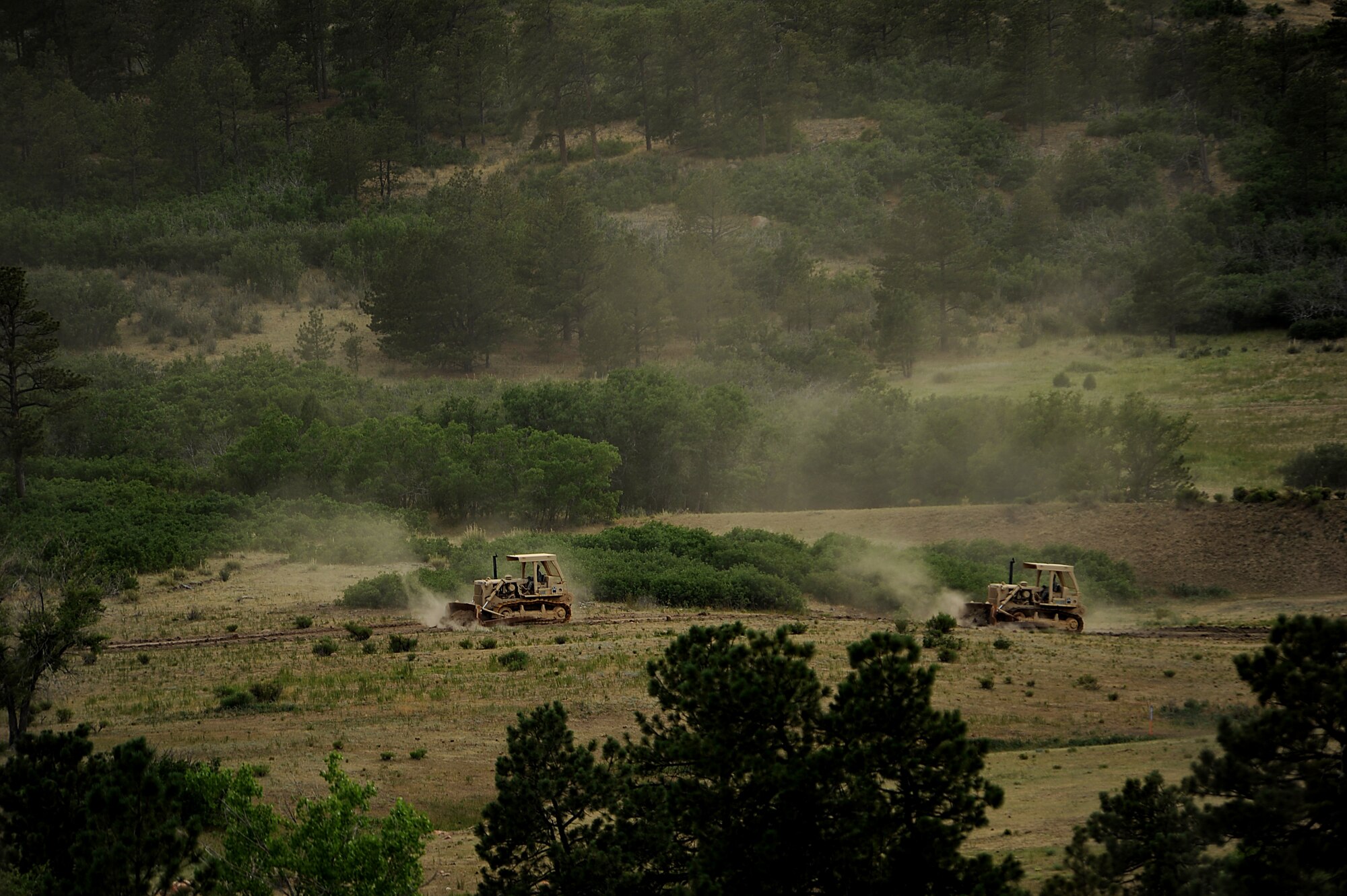 Bulldozers brought in from Fort Carson cut a fire line as firefighters continue to battle several fires that burned into the evening hours in Waldo Canyon on the U.S. Air Force Academy June 27, 2012. The fires, which have burned more than 15,000 acres, began spreading to the southwestern corner of the Academy in the early morning, causing base officials to evacuate residents. (U.S. Air Force Photo by: Master Sgt. Jeremy Lock)