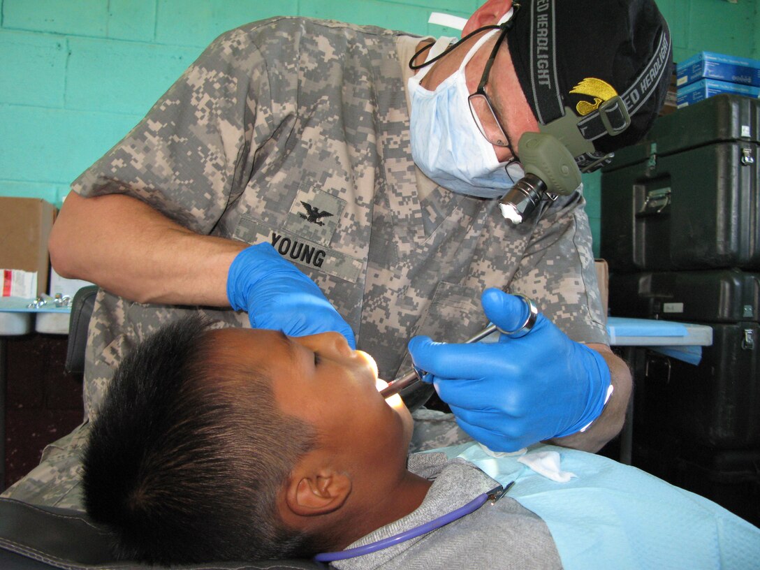 Army Col. (Dr.) Jeff Young from the 133rd Medical Company in Colorado extracts a tooth from a young Guatemalan boy as part of Beyond the Horizon 2012, June 27, 2010. DOD photo by Donna Miles 