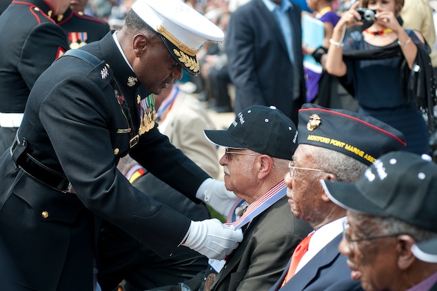 Lt. Gen. Willie Williams, director of Marine Corps staff, presents a Montford Point Marine with a bronze replica Congressional Gold Medal during a special ceremony at the historic parade grounds of Marine Barracks Washington June 28. In 1942, President Roosevelt established a presidential directive giving African Americans an opportunity to be recruited into the Marine Corps. Between 1942 and 1949 approximately 20,000 African American Marines received basic training at the segregated Montford Point instead of the traditional boot camps of Parris Island, S.C. and San Diego, Calif. These men fought for their country with honor and valor that are hallmarks of the Corps, but they were not treated as equals to their white counterparts at the time. Gen. James F. Amos, commandant of the Marine Corps, set out to begin to right this wrong when he invited the Montford Point Marines to the Barracks Aug. 26, 2011 to be the guests of honor at a Friday Evening Parade, bringing their story to the national forefront and starting a chain of events that lead to this historic day.