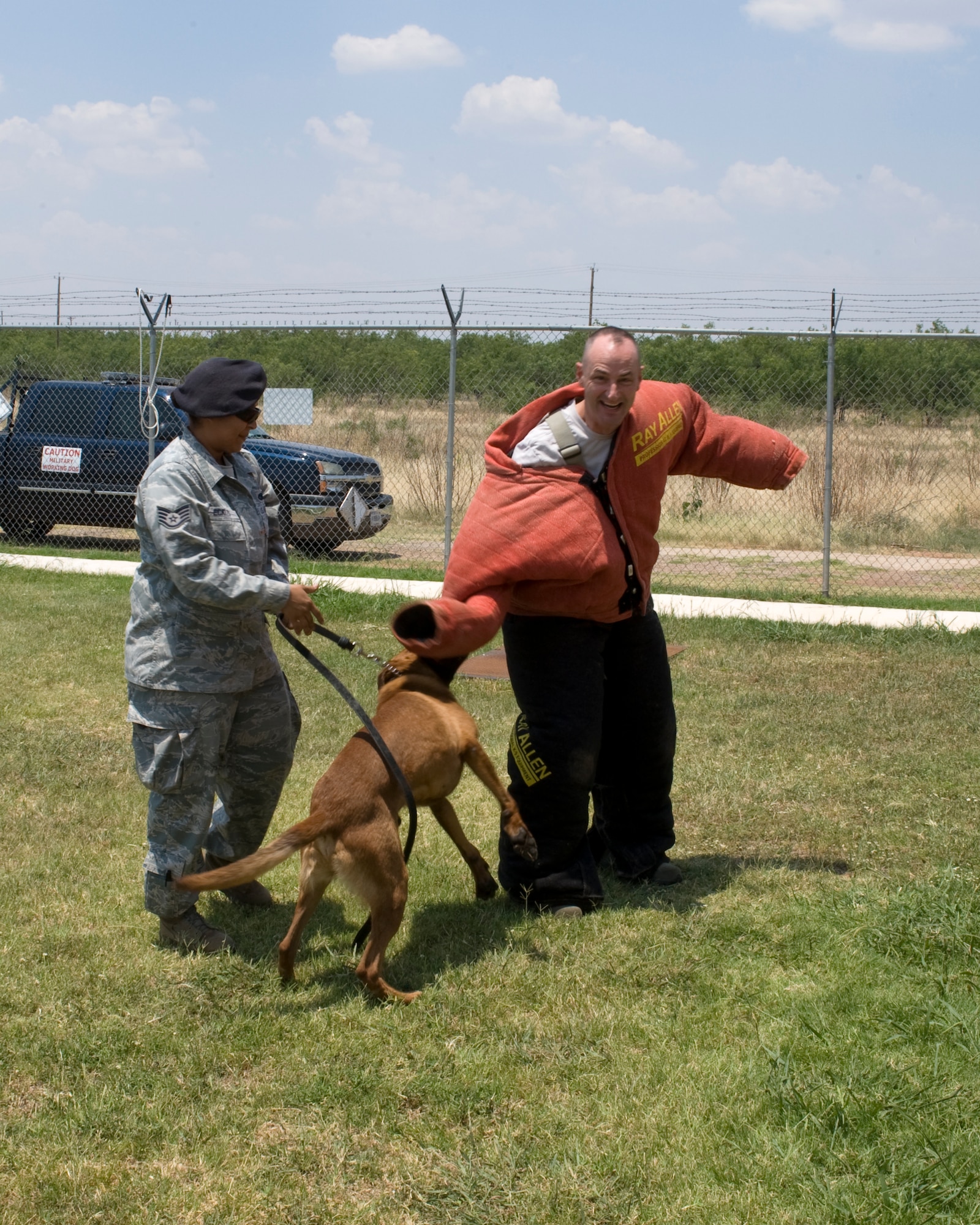 U.S. Air Force Staff Sgt. Patricia Eckles, 7th Security Forces Squadron, left, secures her military working dog, Dewey, while Col. David Béen, 7th Bomb Wing commander, tries to fend him off, June 26, 2012, at Dyess Air Force Base, Texas. Béen received an opportunity to see and feel the capabilities of a military working dog first hand. MWDs are used on patrol, drug and explosive detection, as well as suspect apprehension. (U.S. Air Force photo by Staff Sgt. Richard P. Ebensberger/ Released)