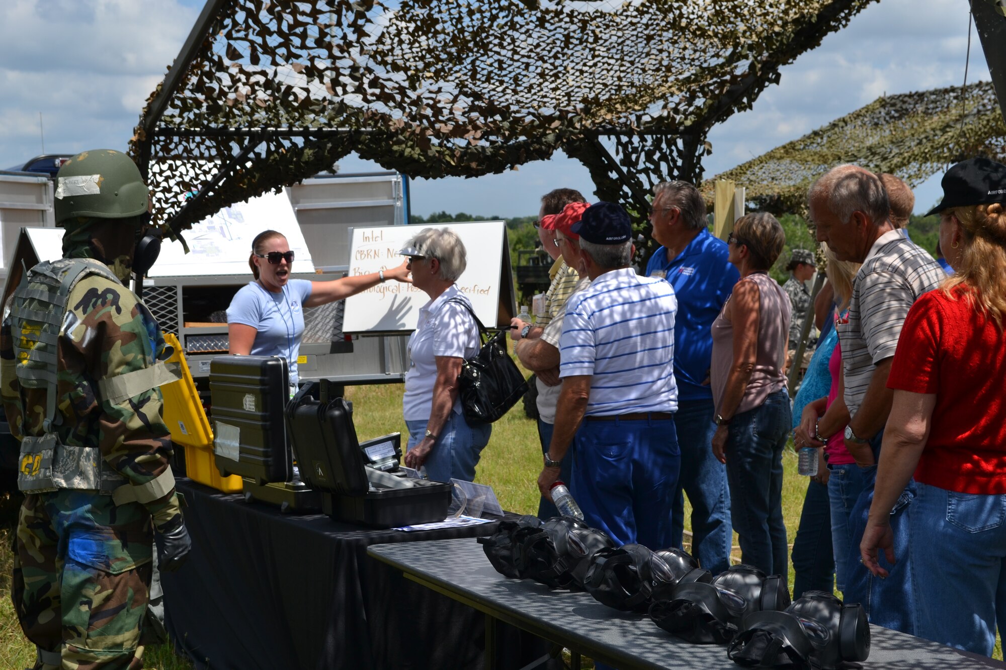 While Staff Sgt. Robert West demonstrates full MOPP Level Four gear, left, Lisa Kuefler, Emergency Management specialist in the 72nd Air Base Wing Civil Engineering Directorate, briefs on-scene emergeny management procedures to members of the Mayors Council of Oklahoma June 22. About 80 members of the council visited Tinker to get a taste of the military life during the 2012 Mayors Summer Conference. The day was full of events including briefings, tours of the Oklahoma Air Logistics Center, static aircraft displays and equipment and skill demonstrations. (Air Force photo by Kathy E. Paine)