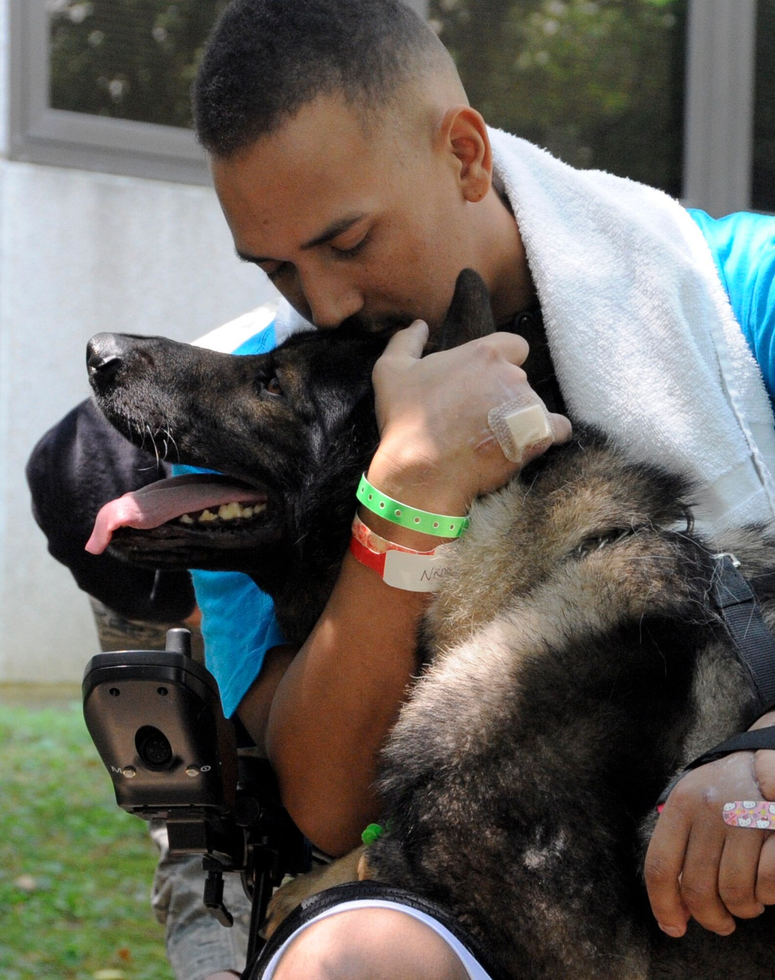 Staff Sgt. Brian Williams hugs military working dog Carly shortly after reuniting with him in the courtyard at Walter Reed National Military Medical Center. Carly stayed by Williams’ side for most of the visit, even jumping his front paws up onto Williams’ lap on several occasions. (U.S. Air Force photos by 2nd Lt. Alexis McGee/Released)