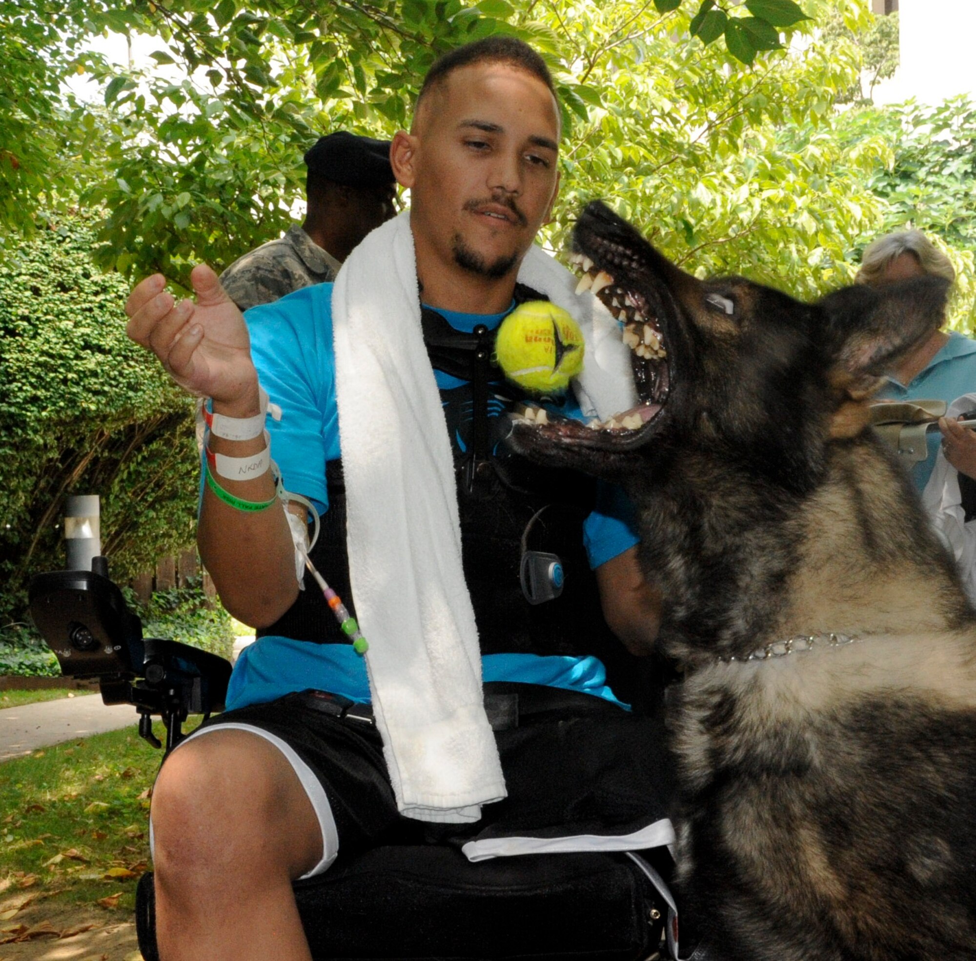 – Staff Sgt. Brian Williams tosses a ball to military working dog Carly in the courtyard at Walter Reed National Military Medical Center. Williams asked his visitors if any of them brought toys for Carly to play with. Since they hadn’t, Williams solved the toy trouble by removing the tennis ball from his walker and tossing it in the air to Carly who “jumped” at the chance to play fetch with his handler. (U.S. Air Force photos by 2nd Lt. Alexis McGee/Released)