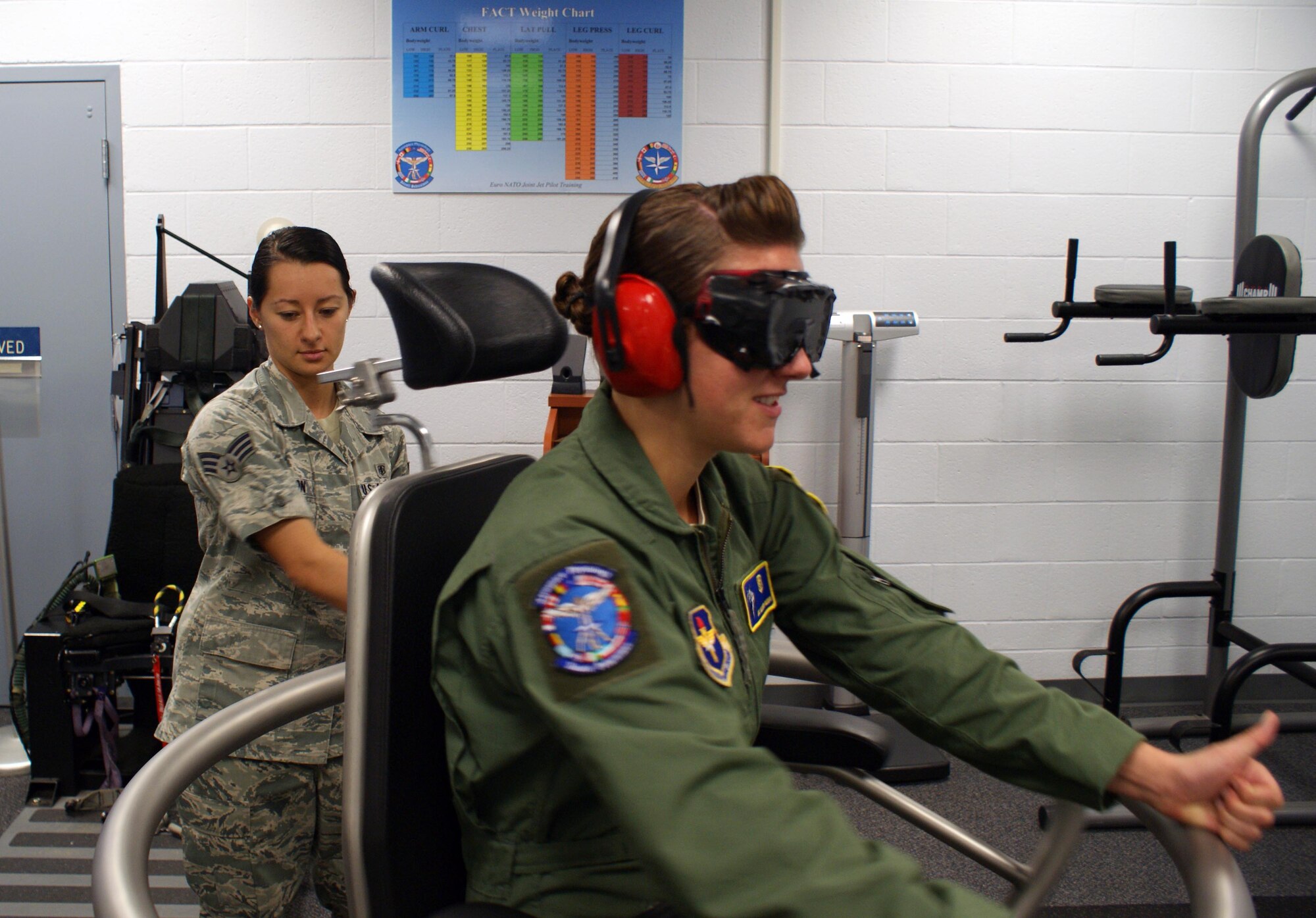 Senior Airman Katia Cordon (left) educates Airman 1st Class Allison Freeman about spatial disorientation during Barany Chair training  at Sheppard Air Force Base, Texas, on June 8, 2012. The spatial disorientation simulator creates the same feelings pilots and aircrew members have while in actual flight. Cordon is an 82nd Aerospace Medicine Squadron aerospace and operational physiology technician. (U.S. Air Force photo/Dan Hawkins)