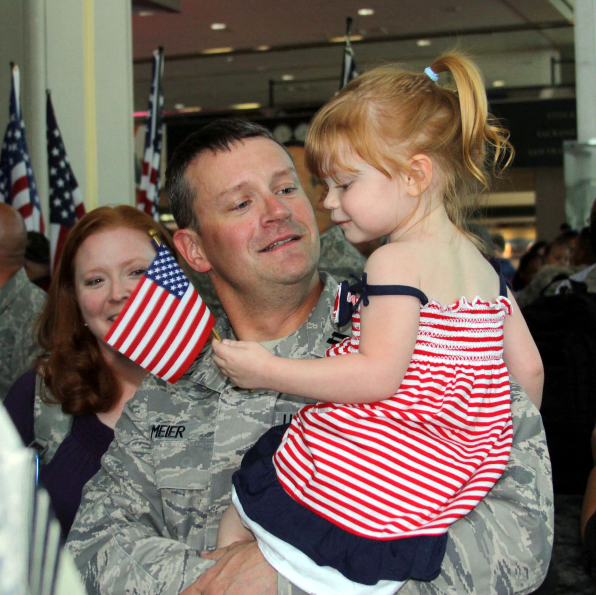 TRAVIS AIR FORCE BASE, Calif. --As his wife smiles behind him, Capt. Joseph Meier holds his little daughter for the first time in six months, at Sacramento International Airport June 10, 2012. Meier, with the 349th Civil Engineering Squadron, returned with a group from Southwest Asia, that included civil engineers from the 349th and 60th AMWs, Travis AFB, and the 940th Wing from Beale. (U.S. Air Force photo/SMSgt. Robert Pfenning)