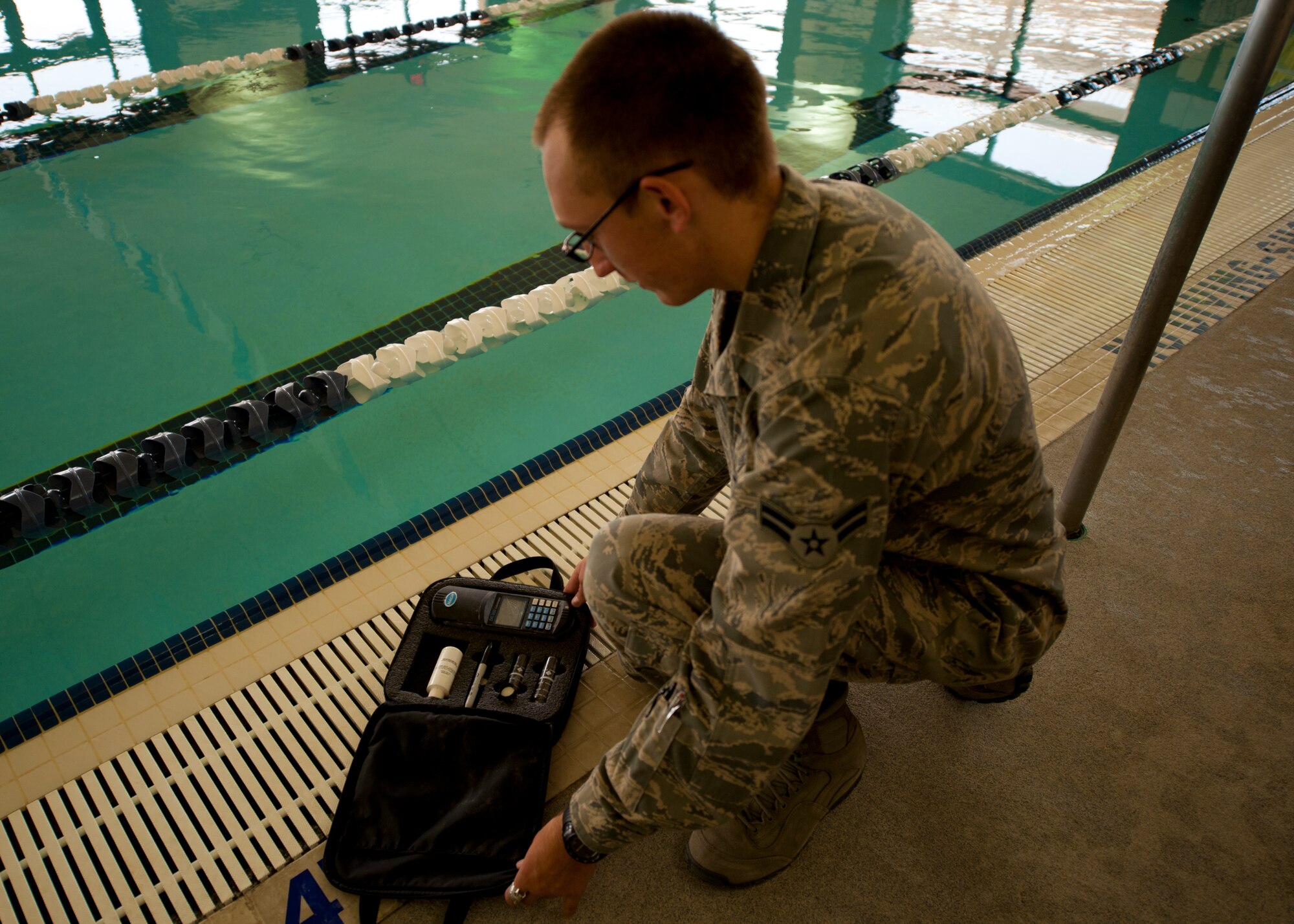 Airman 1st Class Peyton Oesterreich, 49th Aerospace Medicine Squadron bioenvironmental engineer apprentice, opens his hach kit at the Domenici Fitness and Sports Center pool at Holloman Air Force Base, N.M., June 27. The hach kit is used to test water quality and give a proper water analysis to ensure the base pools have safe hydrogen and chlorine levels. In addition to performing water analysis, bioenvironmental engineers also ensure safety of the base and respond to crashes and flight emergencies.  (U.S. Air Force photo by Airman Leah Ferrante/Released)
