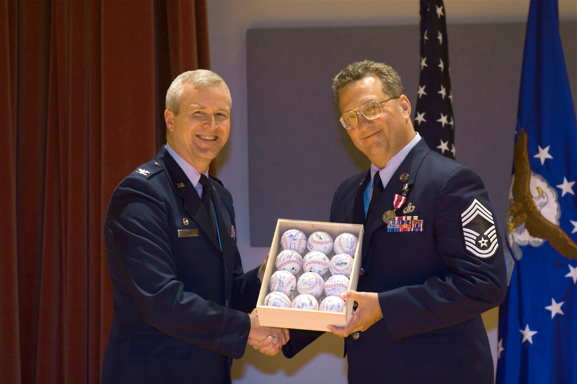 Col. Larry Lang presents Chief Master Sgt. Hones a squadron gift of
baseballs "autographed" by Band members at Chief Hone's retirement ceremony
(AF photo by Master Sgt. Tara Islas)