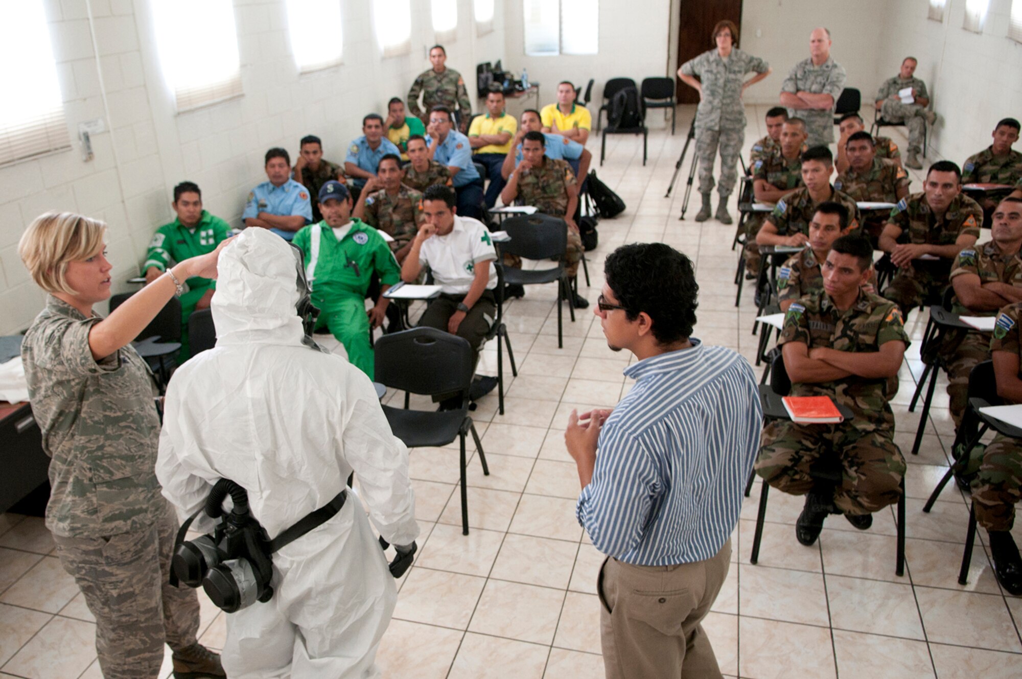 U.S. Air Force Senior Airman Alexa Shimmel (left) demonstrates on Salvadoran Soldier Carlos Alfredo Garcia Duranhow how personal protective equipment is used in an environment that may contain hazardous material as Alfredo Josue Bautista interprets June 26, 2012. Five medical personnel from the New Hampshire Air National Guard traveled here to participate in a Chemical Biological Radiological Nuclear High Yield Explosive Enhanced Response Force Package (CERFP) exchange with local authorities. (N.H. National Guard photo by Tech. Sgt. Mark Wyatt/RELEASED)