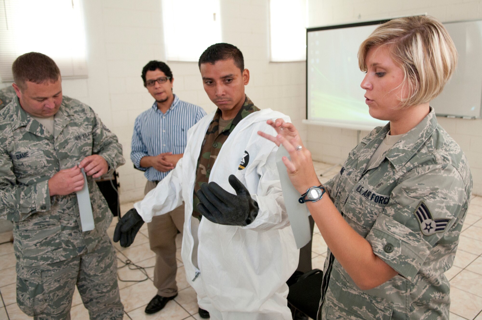 U.S. Air Force Senior Airman Alexa Shimmel (right) demonstrates on Salvadoran Soldier Carlos Alfredo Garcia Duranhow how personal protective equipment is used in an environment that may contain hazardous material as Tech. Sgt. Michael Dame assists June 26. Five medical personnel from the New Hampshire Air National Guard traveled here to participate in a Chemical Biological Radiological Nuclear High Yield Explosive Enhanced Response Force Package (CERFP) exchange with local authorities. (N.H. National Guard photo by Tech. Sgt. Mark Wyatt)