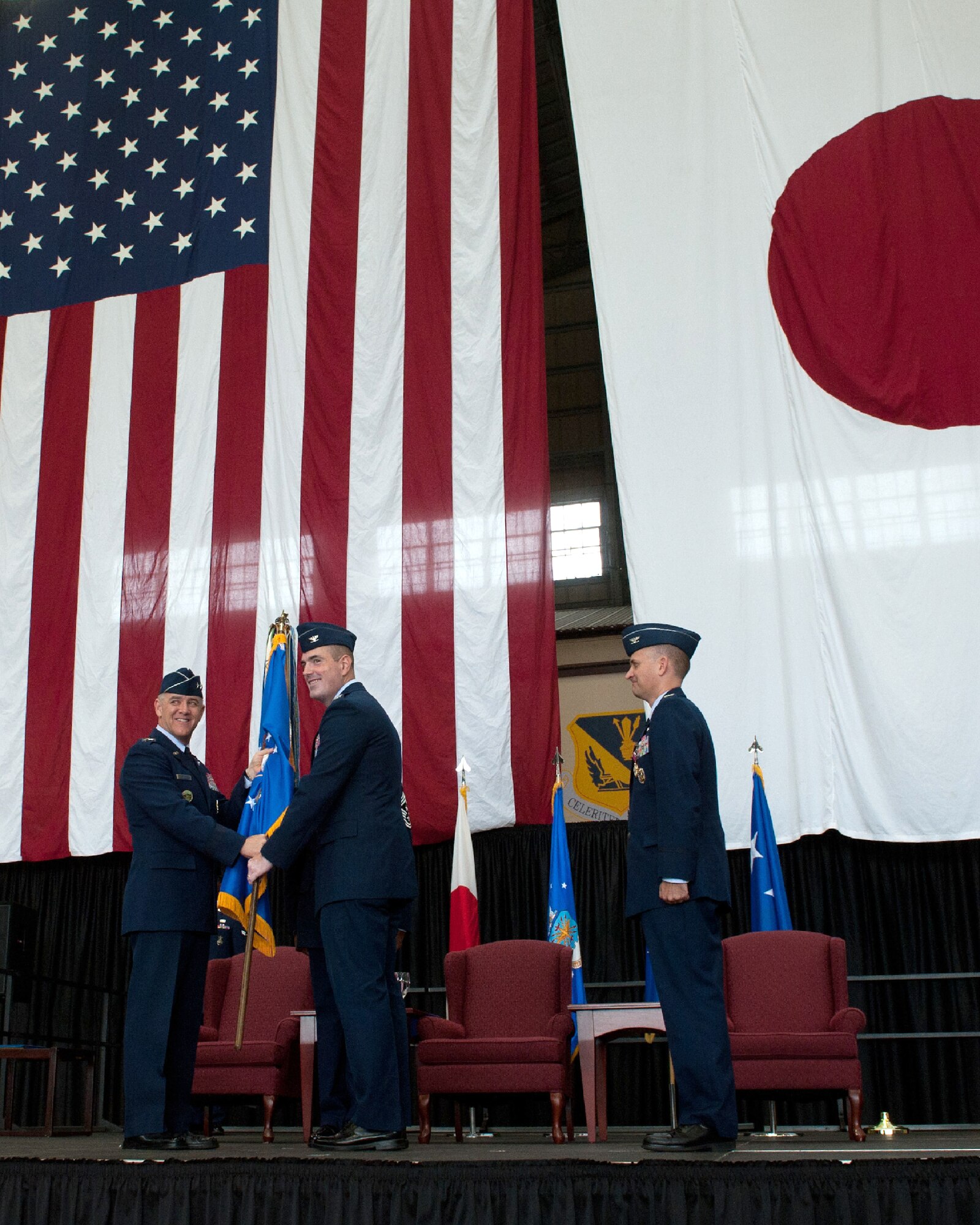 YOKOTA AIR BASE, Japan -- Lt. Gen. Burton Field, 5th Air Force and U.S. Forces, Japan, commander, left, passes the guidon to Col. Mark August, the new 374th Airlift Wing commander, center, during a change of command ceremony June 29, 2012, at Yokota Air Base, Japan. August recently returned from a deployment where he served as the 386th Expeditionary Operations Group commander in Southwest Asia. (U.S. Air Force photo by Airman 1st Class John D. Partlow)
