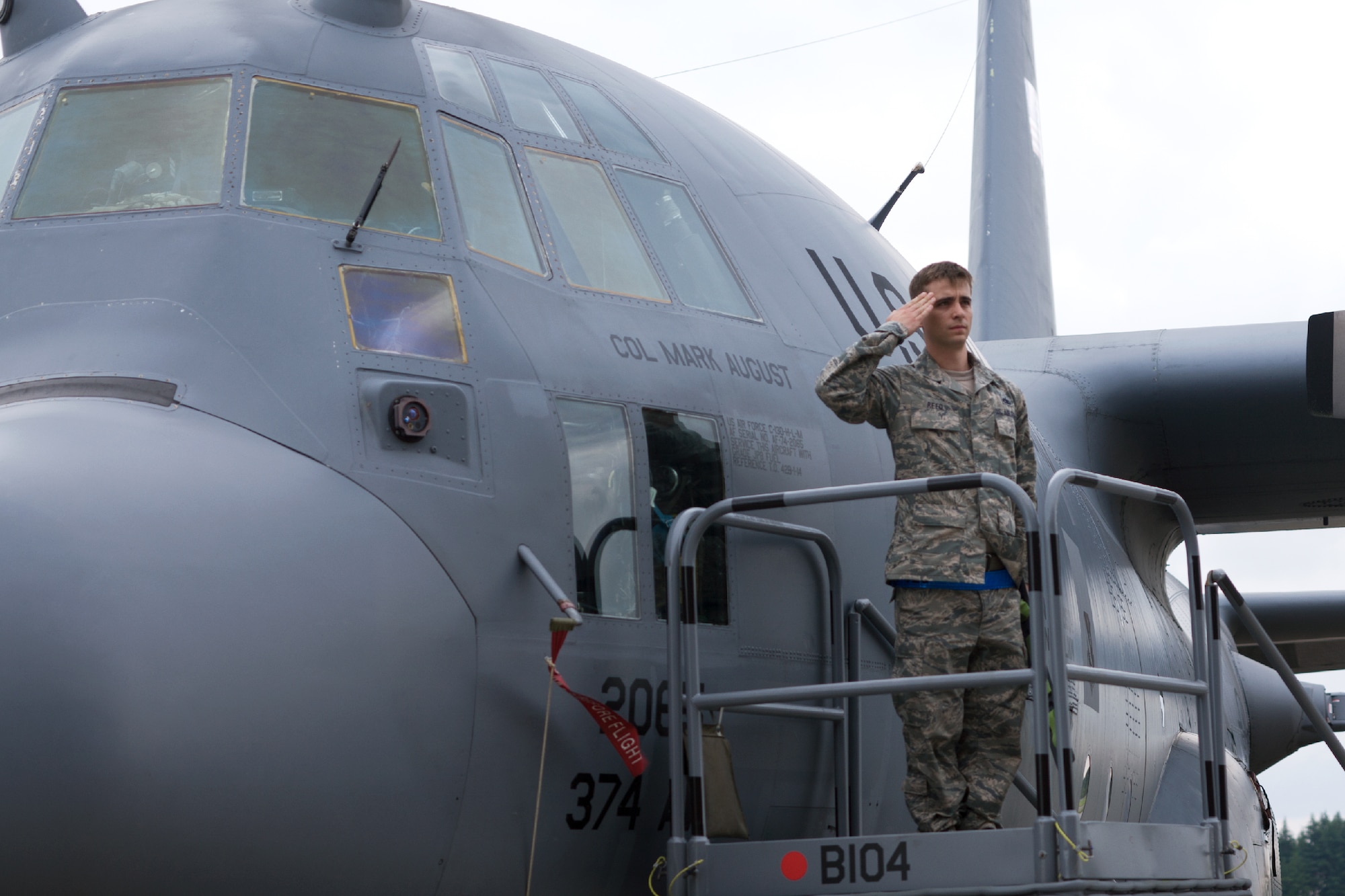 YOKOTA AIR BASE, Japan -- Staff Sgt. Joel Reed, 374th Aircraft Maintenance Squadron dedicated crew chief, salutes Col. Mark "Buzz" August, 374th Airlift Wing commander, after unveiling the commander's name on the wing's flagship C-130 Hercules at the end of the 374 AW change of command ceremony at Yokota Air Base, Japan, on June 29, 2012. The change of command is a traditional military ceremony in which the departing commander assembles his troops for presentation to the incoming commander. (U.S. Air Force photo by Osakabe Yasuo)