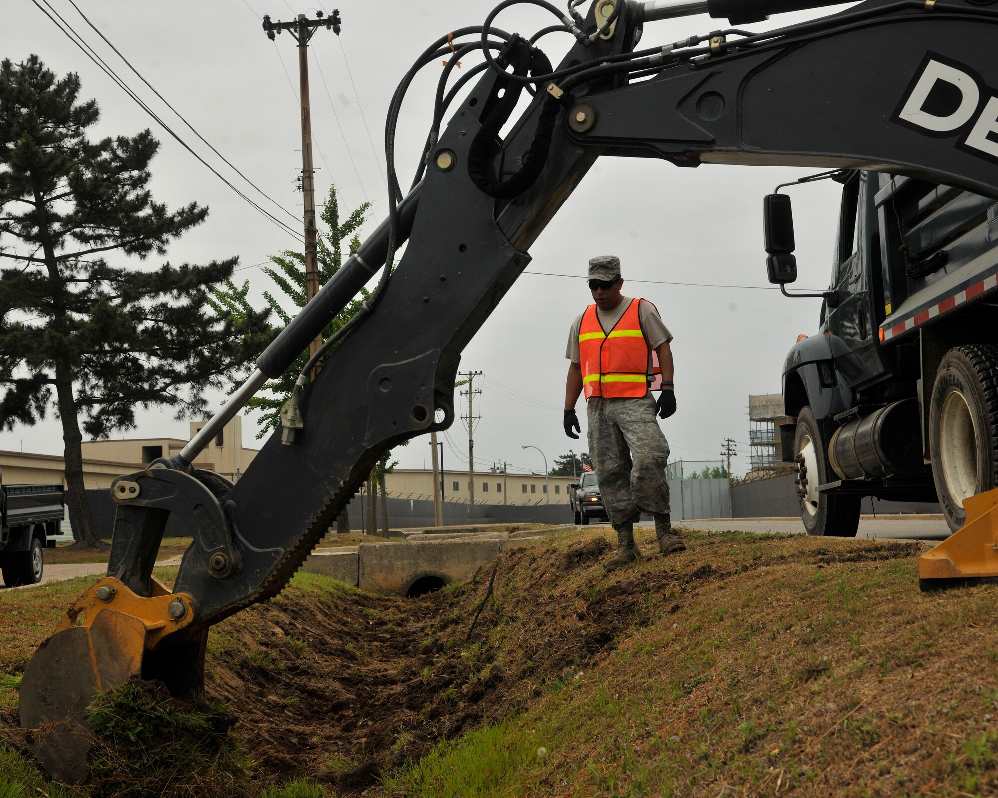 Staff Sgt. Jacob Membrano, 8th Civil Engineer Squadron pavement and heavy equipment journeyman, guides the backhoe where to dig at Kunsan Air Base, Republic of Korea, June 28, 2012. The goal of this project is to maintain and improve the quality of the drainage ditches for monsoon season. (U.S. Air Force photo/Senior Airman Marcus Morris)