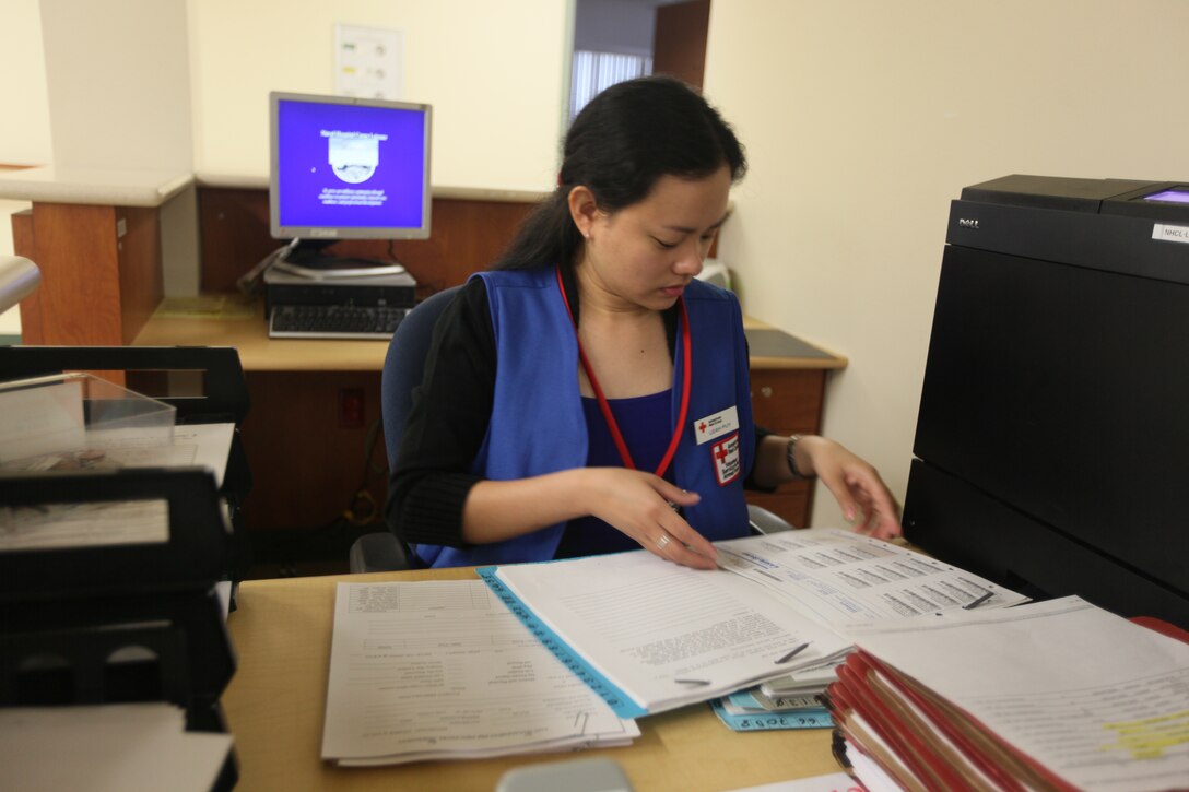 Leah Puy, a volunteer with the American Red Cross aboard Marine Corps Base Camp Lejeune, sorts through files as she helps Naval Hospital Camp Lejeune personnel schedule appointments, March 1. March is American Red Cross Month, and marks more than 100 years of dedicated service to military personnel and disaster victims.