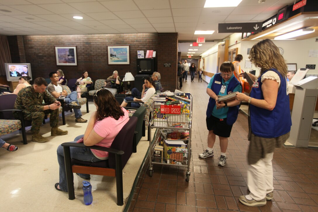 Dawn Hinton (far right) and Dana Gayak, American Red Cross volunteers, both put in two days of volunteer work by handing out books, magazines and coloring pages at Naval Hospital Camp Lejeune, March 1.