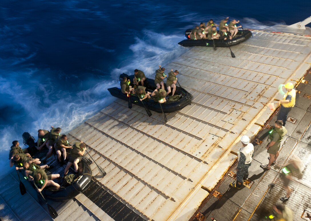 Marines from the 31st Marine Expeditionary Unit push off the stern gate of the forward-deployed amphibious dock landing ship USS Tortuga (LSD 46) in combat rubber raiding craft (CRRC) during a night exercise.