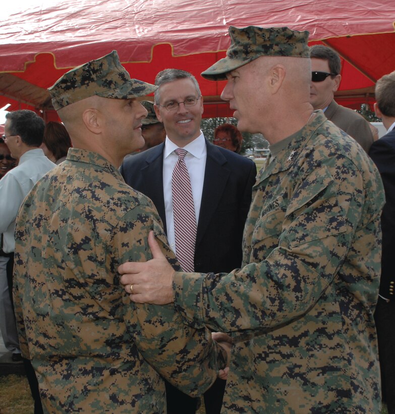 Maj. Gen. Charles L. Hudson, commanding general, Marine Corps Logistics Command, right, congratulates Col. Stephen Medeiros, commander, Marine Depot Maintenance Command, on his new unit at Schmid Field, Feb. 23, while Trent Blalock, deputy commander, MDMC, looks on.