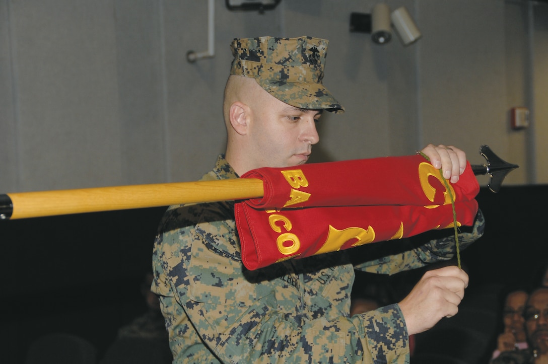 Gunnery Sgt. Gary Gilbert, band master, Albany Marine Band, furls the band’s colors for deactivation at the Base Theater, Feb. 24.